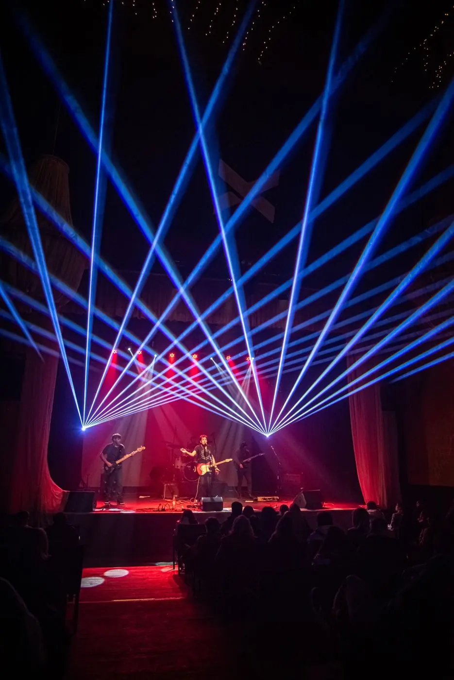 Recital de banda en vivo en teatro con láseres azules y sonido profesional